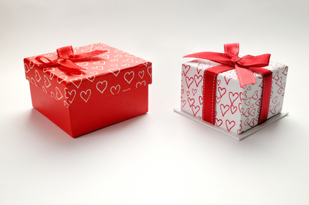 Two decorative gift boxes with red ribbon and hearts printed. Top view. White isolated background.の写真素材
