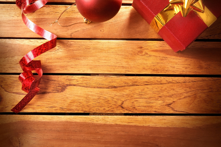 Red Christmas decoration on a table wooden slats. With red gift box, red ball and ribbon. Top view. Horizontal composition.の写真素材