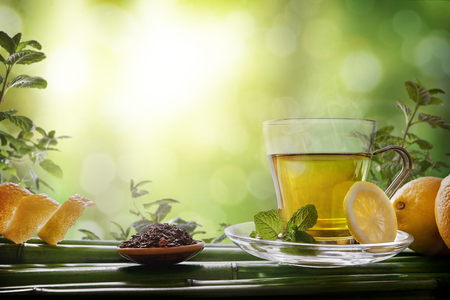Glass cup green tea with mint and lemon on bamboo in nature scene. Horizontal composition. Front view.の写真素材