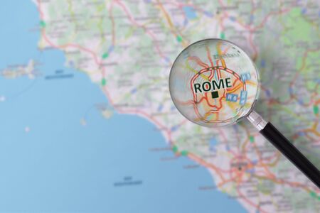 Map of Rome consulted with a magnifying glass highlighting the name of the cityの写真素材