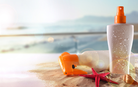 Two suncream with starfish and shell on sand in glass table in terrace overlooking beach and sun shine. Horizontal composition. Front viewの写真素材