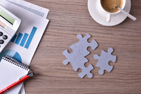 Representation of developing a business idea. Business table with office objects and colorful puzzle.Top viewの写真素材