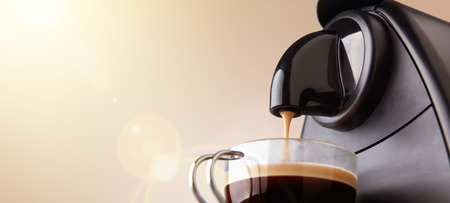Espresso machine making coffee in a glass cup and beige gradient background. Low level, panoramic viewの写真素材