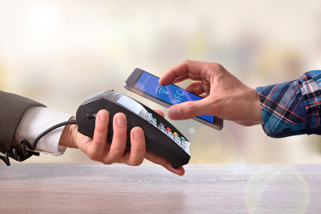 Customer paying a merchant with mobile phone with NFC technology. Top view. Horizontal composition.の写真素材
