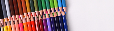 Background colored pencils lined up palette with tips facing each aligned diagonally on white table. Top and panoramic view.の写真素材
