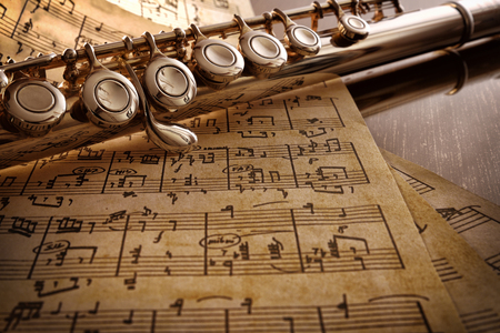 Flute and old handwritten sheet music on reflexive black table. Horizontal composition. Elevated viewの写真素材