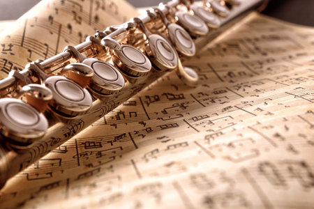 Transverse flute and old handwritten sheet music on black table. Horizontal composition. Front elevated viewの写真素材