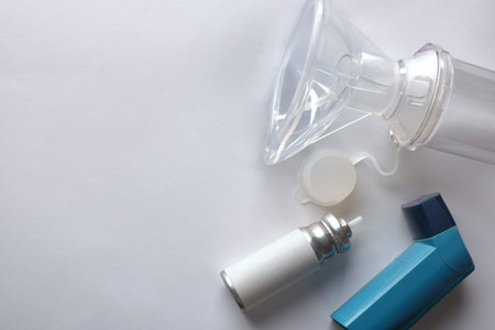 Cartridge and blue medicine inhaler and inhalation chamber with silicone mask on white table. Top...