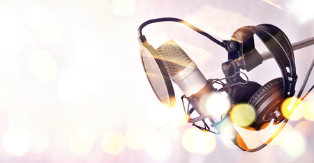 Close up studio condenser microphone with pop filter and anti-vibration mount behind a glass with highlights. Side viewの写真素材