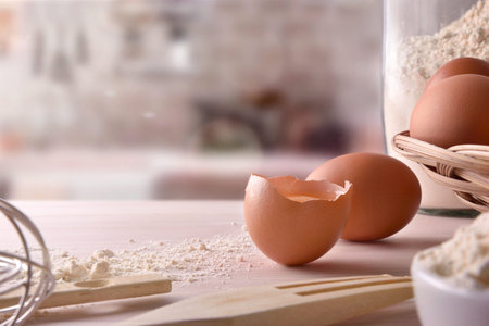 Fresh eggs on the wooden bench of a kitchen and cooking utensils. Front view. Horizontal composition