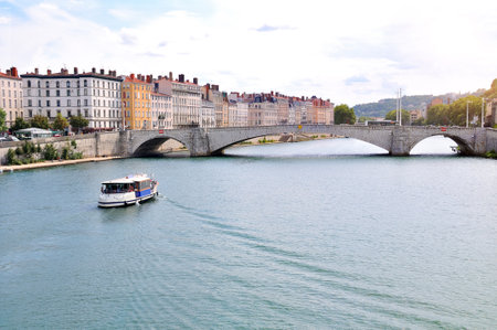 Boat sailing on the Saone River with the Bonaparte bridge and houses in lyon France. Horizontal compositionのeditorial素材