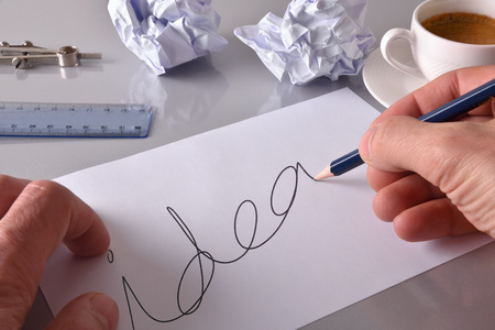 Concept worker developing an idea on his workbench. Sheet with idea message on gray office table with crumpled sheets and coffee in the background. Elevated view. Horizontal compositionの写真素材
