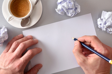 Worker developing an idea on his workbench. Concept search for ideas in business. Blank sheet on gray office table with crumpled sheets and coffee in the background. Top view. Horizontal compositionの写真素材