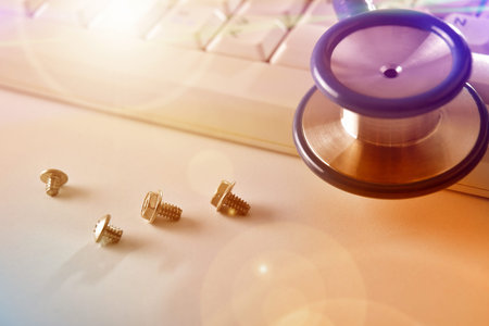 Concept of repairing computers and devices with keyboard, screws and stethoscope background....