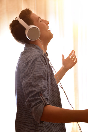 Head profile teenager listening to music with headsets and dancing in the living roomの写真素材