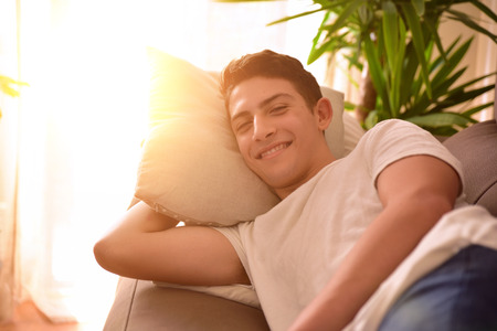 Man lying comfortably on the sofa in a living room. Concept of freedom comfort and tranquility. Side viewの写真素材