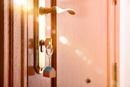 Entrance door detail of a house with keys in the lock with golden light effect. Lateral viewの写真素材