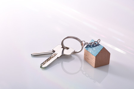 Keys with a house-shaped keyring on a white methacrylate table of a real estate agentの写真素材