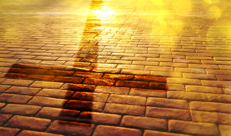Representation of the way of salvation in the Christian religion with shadow of the cross on stone slabs and golden reflection of the sunの写真素材