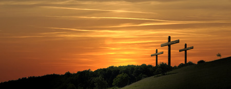 Religious illustration with three backlit crosses with golden glitter and bokeh and nature landscape background. Horizontal compositionの写真素材
