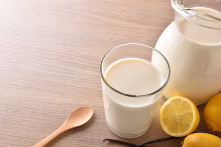 Glass of milk and jug on wooden bench in a rustic kitchen. Horizontal composition. Elevated top viewの写真素材