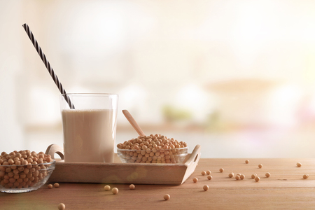 Reptientes with soy milk and grains on a wooden table in white kitchen background. Alternative milk concept. Front view. Horizontal compositionの写真素材