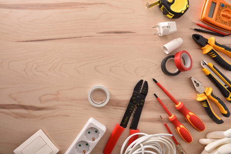 Variety of electricity tools on a wooden table with space on the left. Horizontal composition. Top...