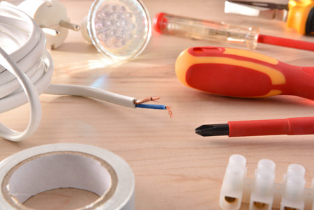 Composition of tools for electrical repairs on wooden table. Horizontal composition. Elevated view.
