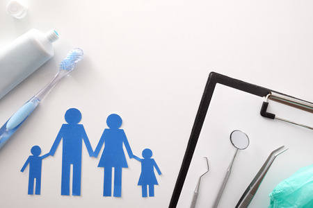 Concept of family dental insurance with representative elements and oral tools on a white table. Horizontal composition. Top viewの写真素材