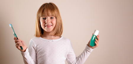 Smiling girl with toothbrush and toothpaste on isolated brown. Horizontal composition.の写真素材