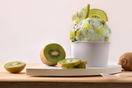 Kiwi ice cream cup decorated with pieces and slices of kiwi fruit on a wooden table. Horizontal...