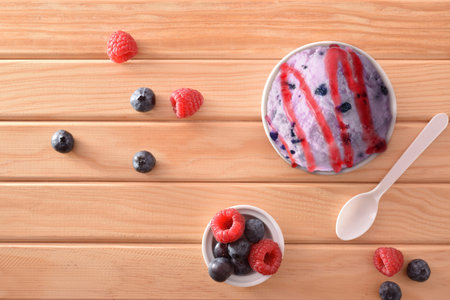 Berries ice cream cup decorated with blueberries and raspberries on a wooden table. Horizontal...