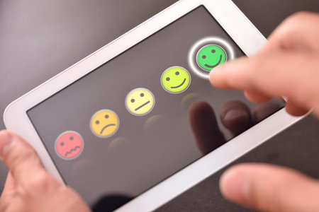 Man valuing a service on a device with emoticons on black screen. Horizontal composition. Top view.