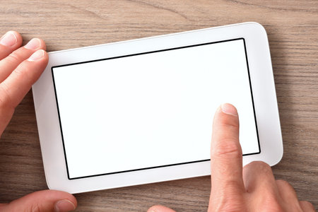 Hands using white tablet with white screen on wood table close up. Horizontal composition. Top view