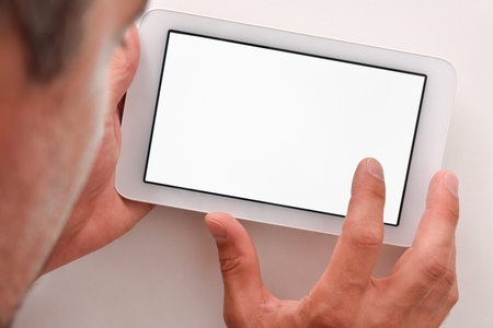 Man using white tablet with white screen on wood table close up. Horizontal composition. Top view