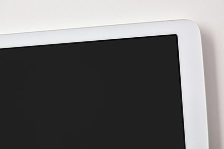 White tablet with black screen on white table close up. Horizontal composition. Top view