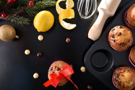 Freshly homemade chocolate muffins for Christmas parties on black table with lemos and kitchen items. Horizontal composition. Top view.の写真素材