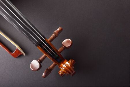 Violin pegbox and bow on black textured table Top view. Horizontal composition.の写真素材