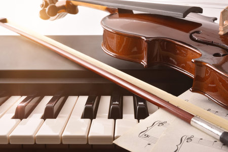 Violin bow and sheet music on piano keys. Concept of interpretation of piano music and string...