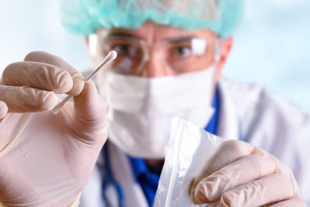 Medical person with individual protection elements taking an oral sample to analyze with a cotton...