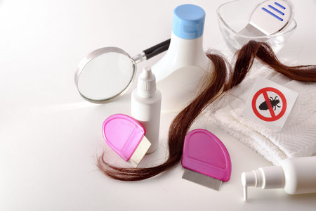 Hairdressing products for lice treatment on white table and window background with venetian blind....