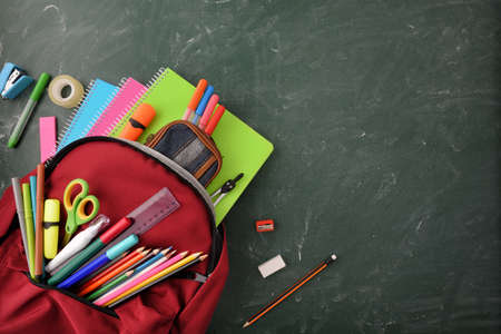 Backpack full of school supplies on green blackboard with blank space for writing top viewの写真素材