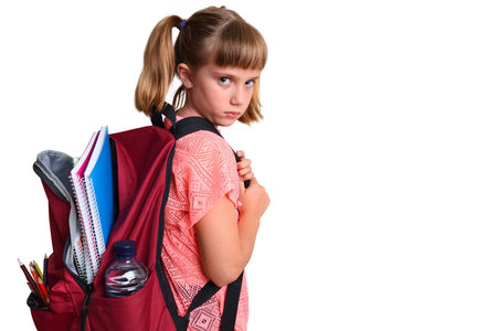 Little and sad girl with backpack on her back with school supplies with isolated white background