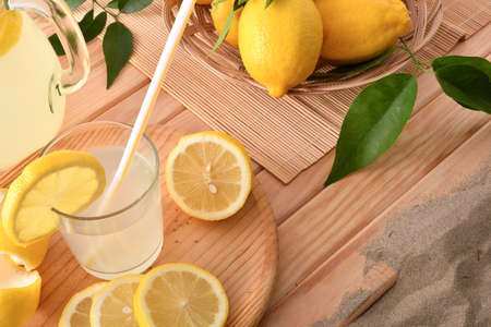 Freshly squeezed lemonade in glass on wooden base with lemons in beach resort. Elevated view. Horizontal composition.の写真素材