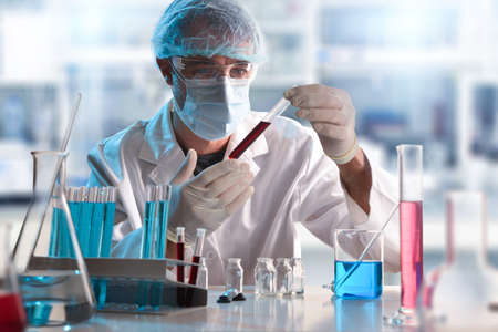 Scientist in laboratory looking at a sample in a test tube. Horizontal composition. Front view.の写真素材