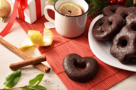 Heart and star shaped chocolate cookies on white plate and cinnamon sticks and mint on wood table....