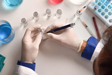 Medical worker writing on vial on laboratory table. Top view. Horizontal composition.