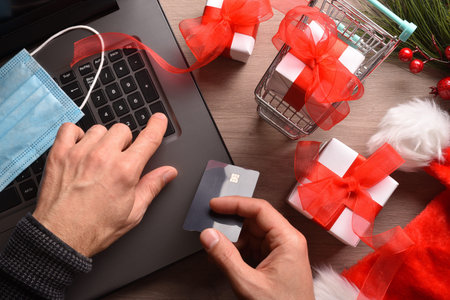 Concept of person doing christmas shopping online at home safely by covid-19 from a laptop. Top...