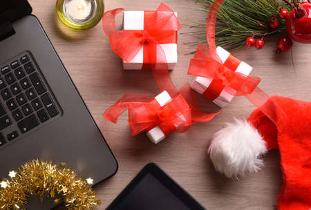 Composition with gift packages on a wooden table with Christmas decorations and digital gadgets. Horizontal composition. Top view.の写真素材