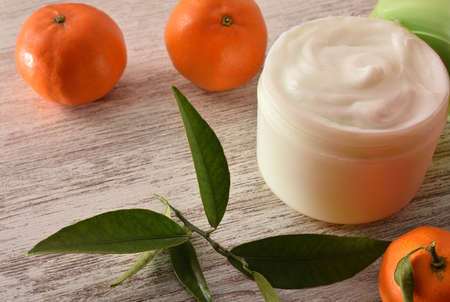 Natural skin cream with tangerine extract with fruit and leaves on wood table. Elevated view.の写真素材